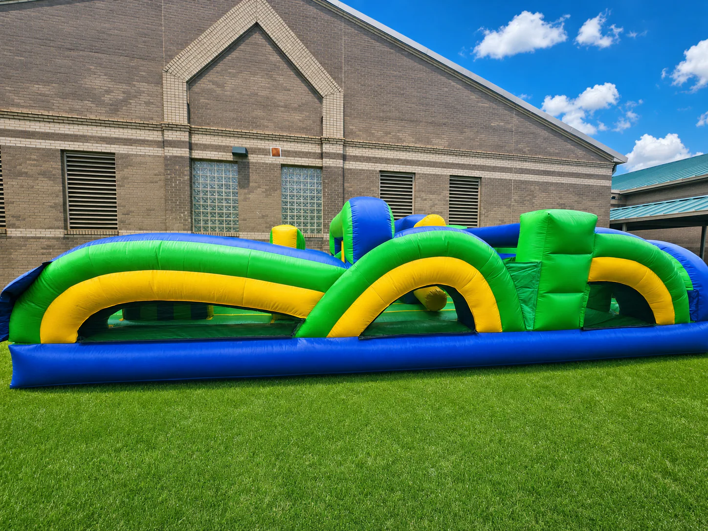 Wow Inflatables green blue yellow inflatable obstacle course rental side view at outdoor event in Middle Georgia — Veteran-Owned party rentals