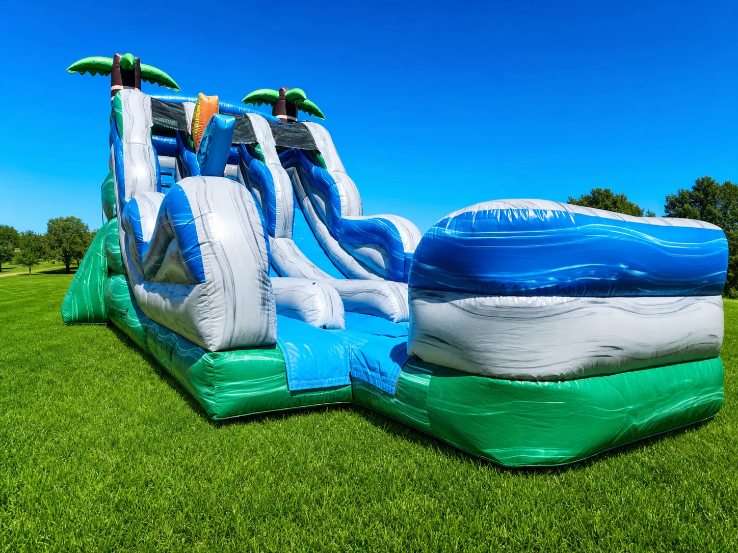 Wow Inflatables tropical dual lane inflatable water slide with palm trees and splash pool rental at outdoor summer event in Georgia