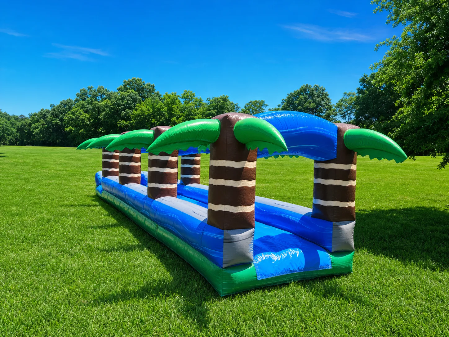 Wow Inflatables tropical palm tree inflatable slip n slide dual lane rental on green grass at outdoor summer event in Middle Georgia