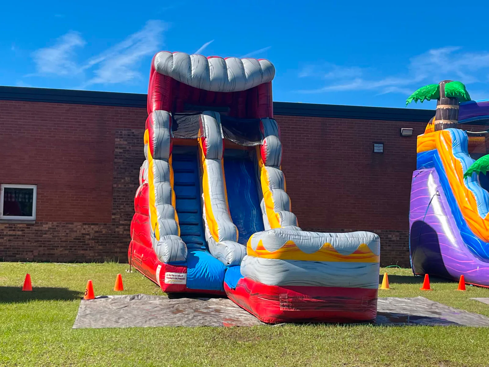 Wow Inflatables red and gray volcano inflatable water slide with steep single lane and splash pool rental at outdoor event in Byron Georgia