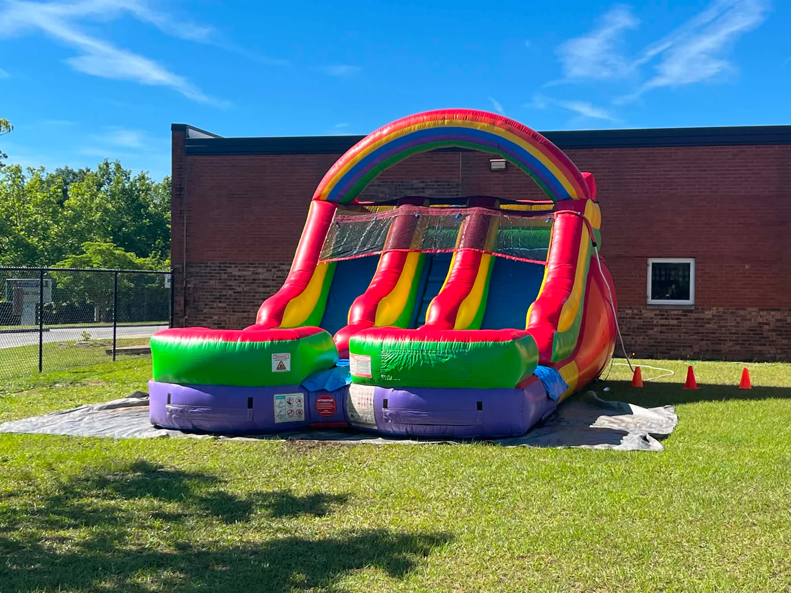 Wow Inflatables rainbow double lane water slide with arched rainbow top and dual racing lanes and splash pool rental at outdoor event in Milledgeville Georgia