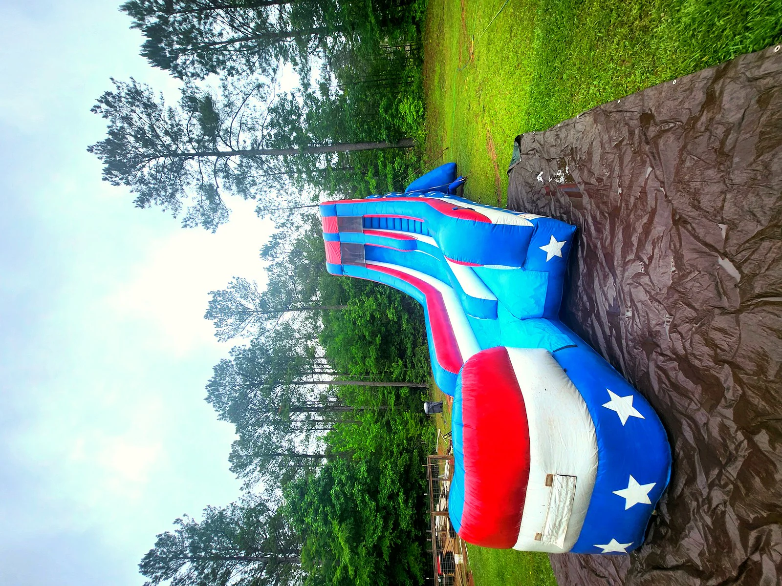 Wow Inflatables patriotic red white and blue American flag water slide rental set up in backyard in Sharpsburg Georgia — tall single-lane inflatable water slide with stars and splash pool at outdoor party in Coweta County