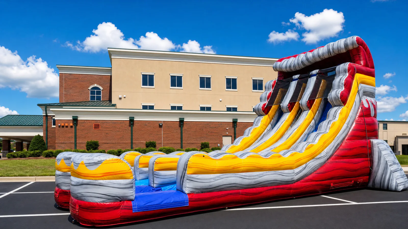 Wow Inflatables fiery red and yellow inflatable water slide rental with dramatic wave patterns set up in commercial parking lot in Macon Georgia — large water slide rental Middle Georgia