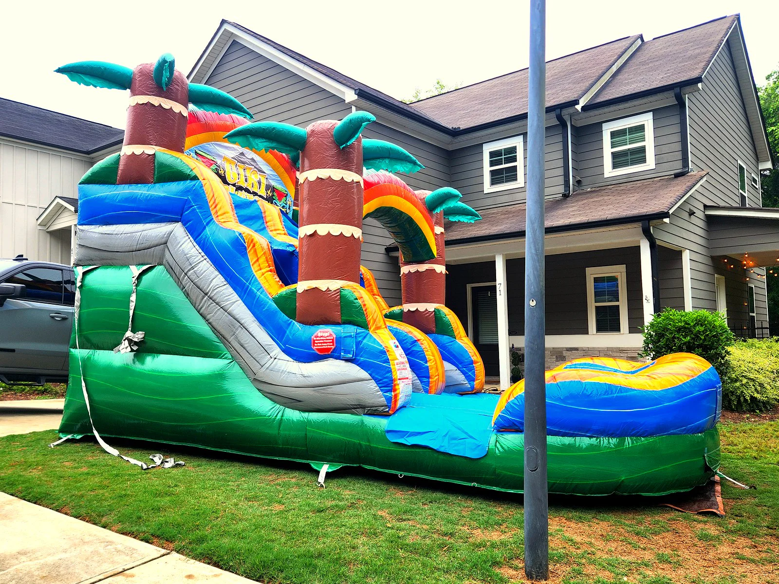 Wow Inflatables Tiki Plunge water slide rental set up in front yard at residential birthday party in Newman Georgia — tropical themed inflatable water slide with palm trees and splash pool