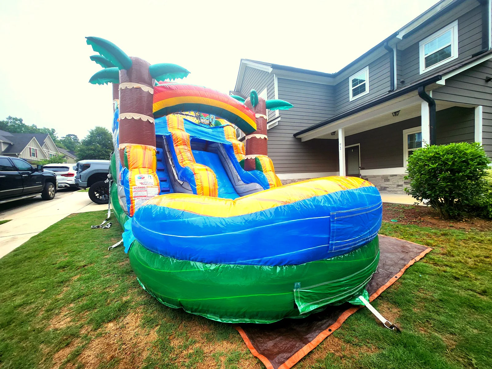 Wow Inflatables Tiki themed inflatable water slide with pool set up in backyard in Newman Georgia — tropical palm tree water slide rental for birthday party in Coweta County