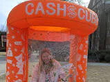 Wow Inflatables cash cube money machine rental at corporate event in Georgia — orange inflatable cash booth with bills flying inside