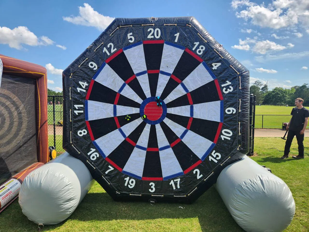 Wow Inflatables giant inflatable dart board game rental at outdoor event in Georgia — massive black and white inflatable dartboard with velcro balls for all ages