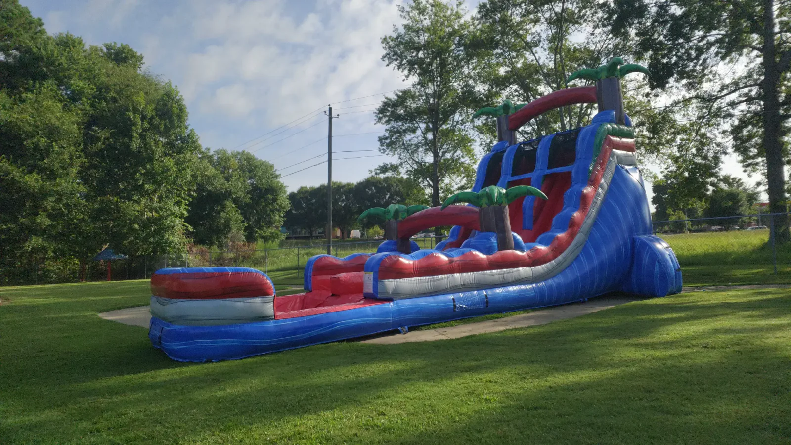 Wow Inflatables 22-foot dual lane water slide rental at summer outdoor event in Middle Georgia — large blue and red commercial water slide with splash pool on green grass