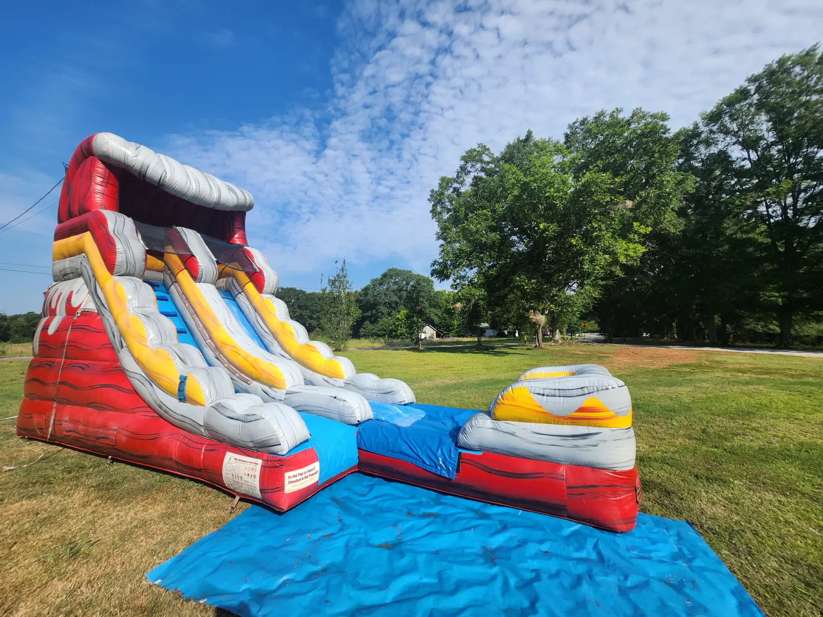 Wow Inflatables red and gray fireball inflatable water slide rental at backyard party in Forsyth Georgia — single lane commercial water slide with splash pool
