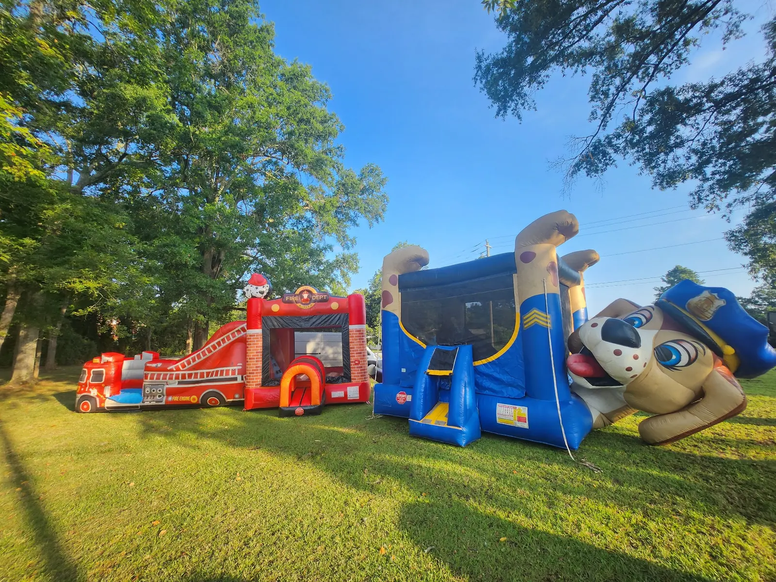 Owner-supplied wide photo of fire truck and police dog themed inflatables set up together for a Middle Georgia event