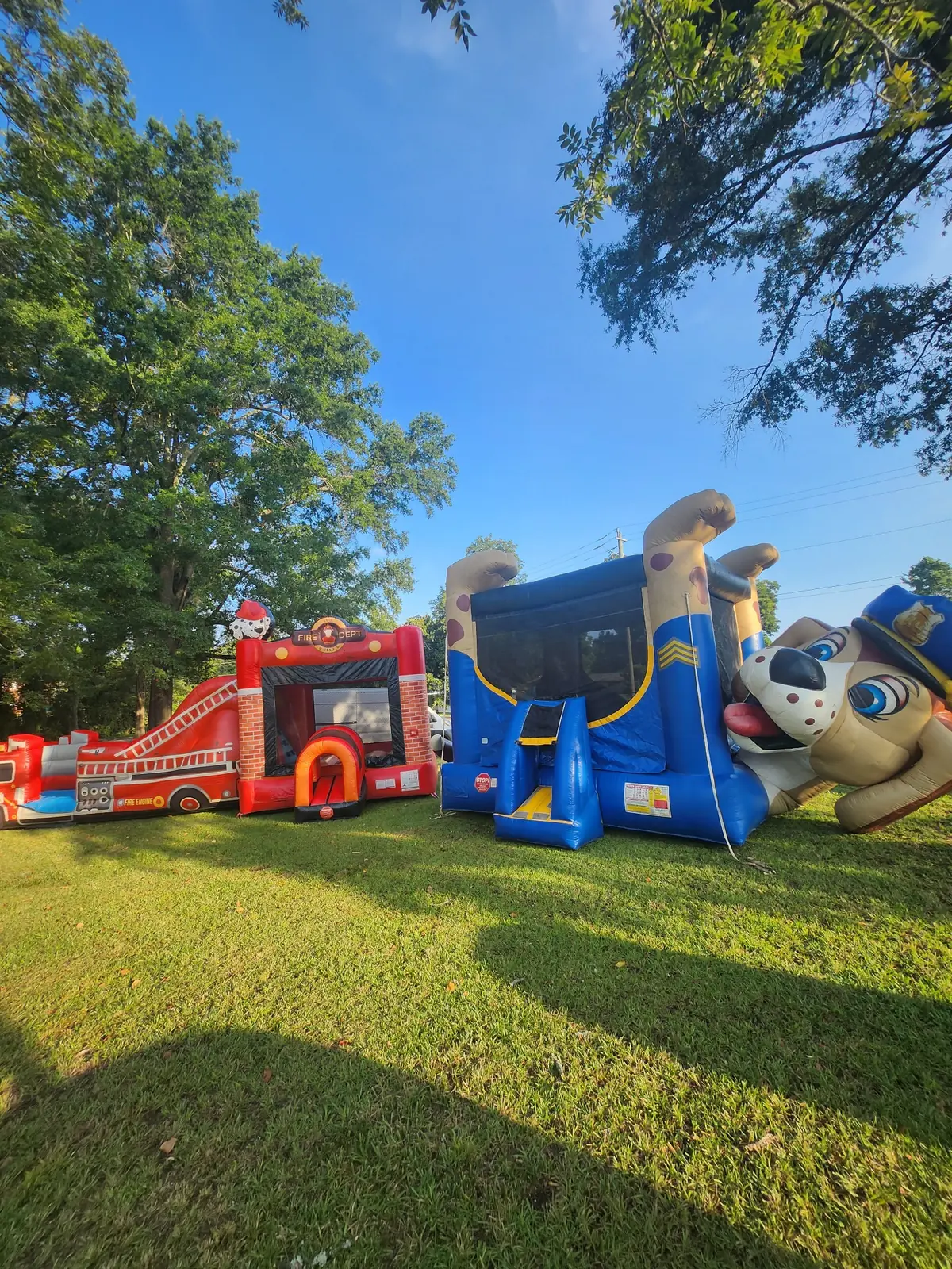 Owner-supplied vertical photo of fire truck and police dog themed bounce houses for Middle Georgia events
