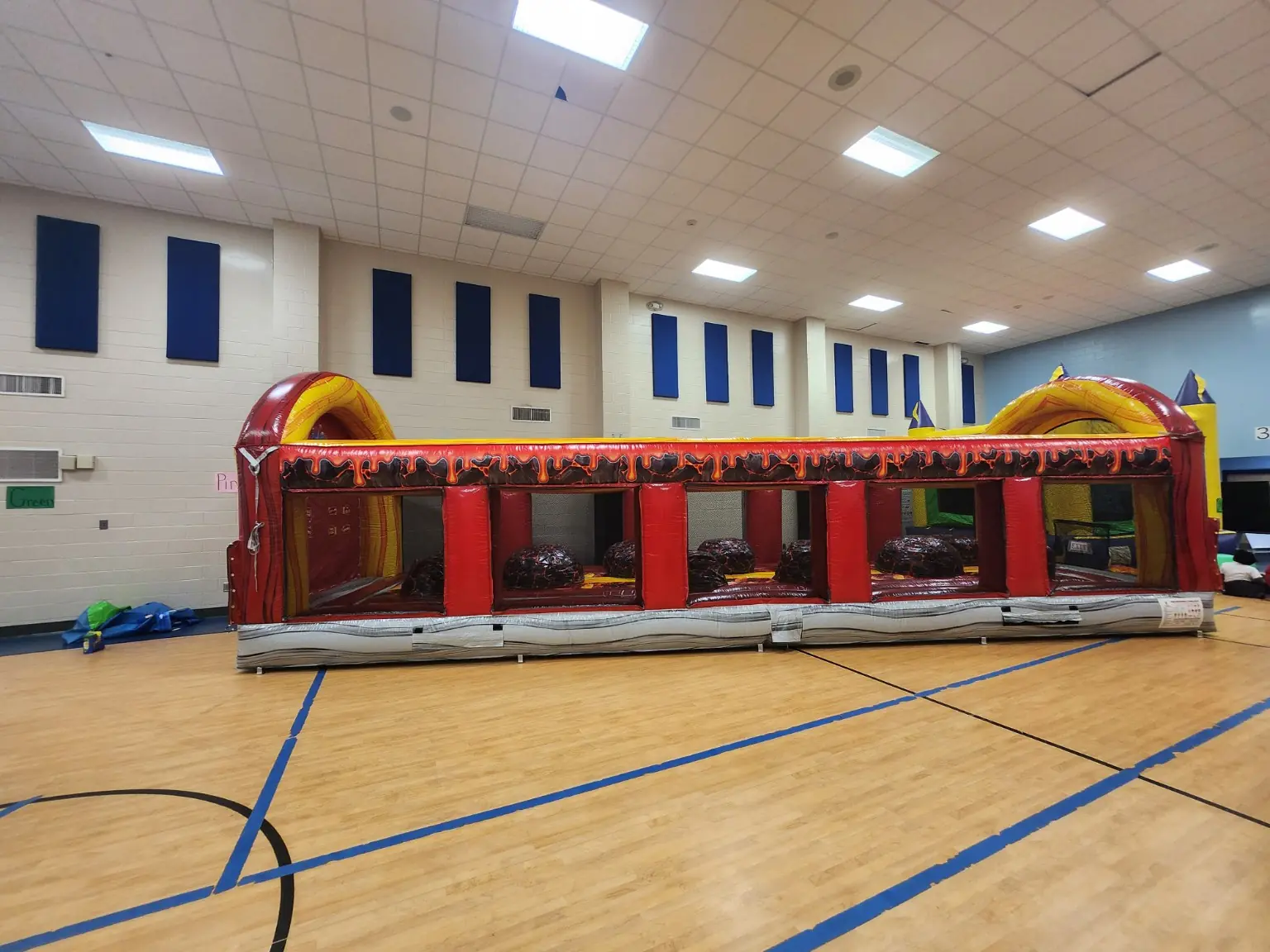 Side view of the Floor Is Lava inflatable obstacle course set up inside a gymnasium