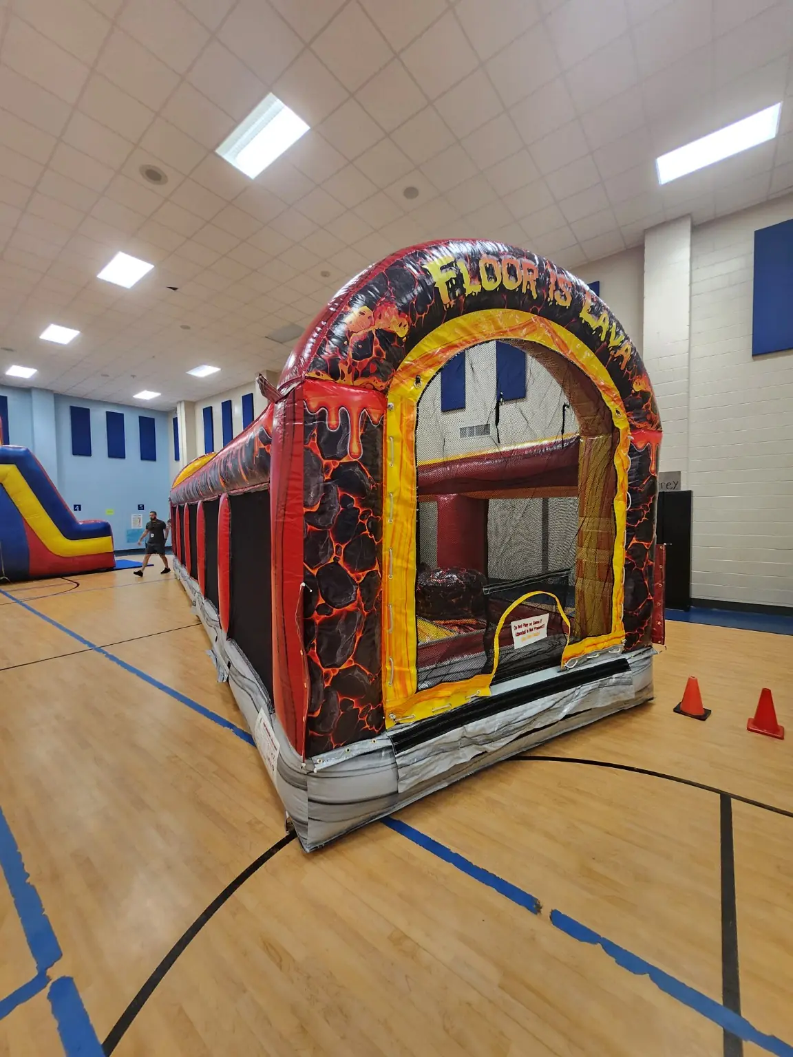 Angled entrance view of the Floor Is Lava inflatable obstacle course inside a gymnasium