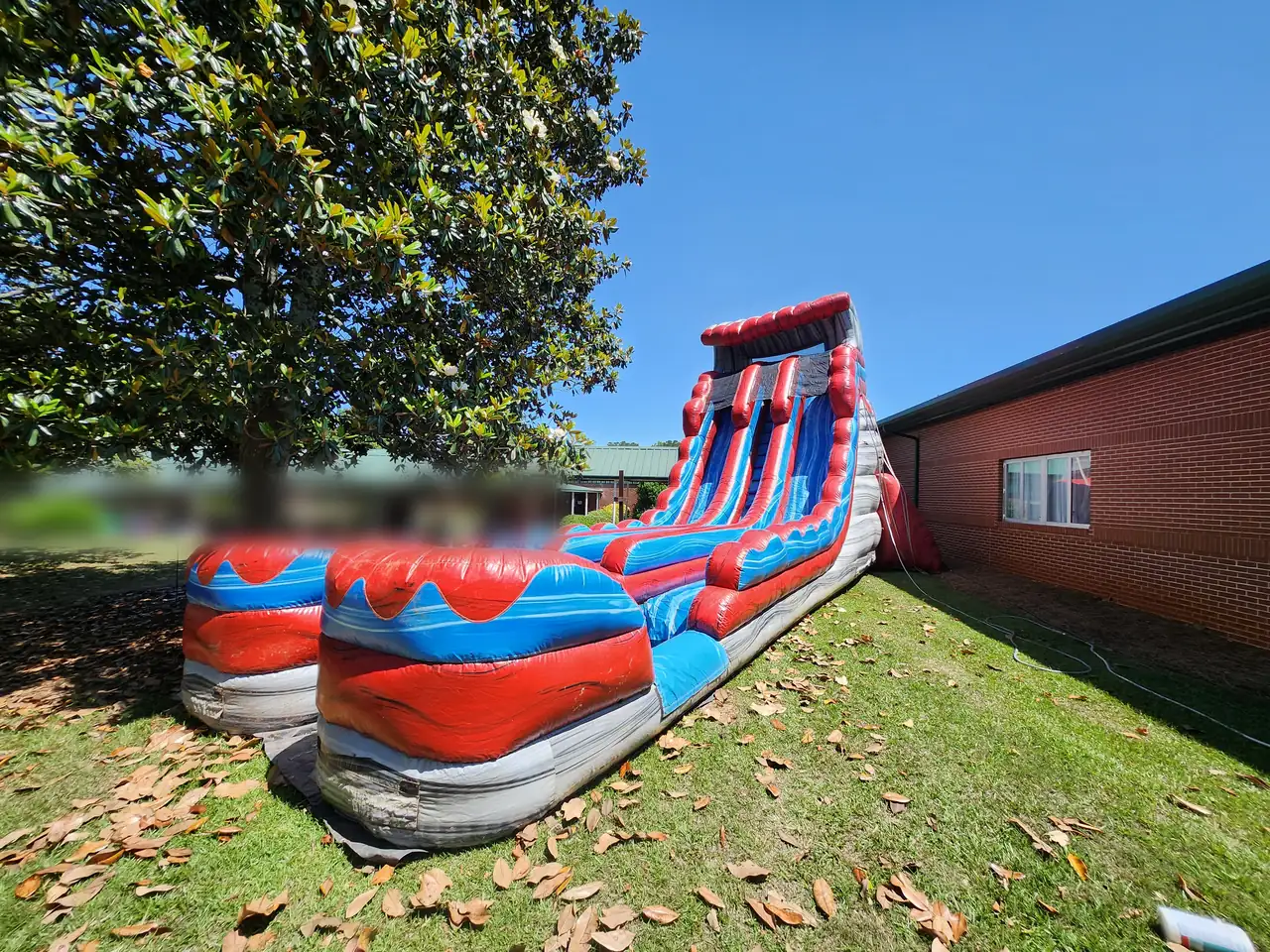 Red, blue and gray dual-lane water slide set up dry under a magnolia tree at St. George's Episcopal School in Milner