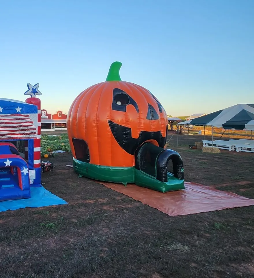 Wow Inflatables Pumpkin Bounce set up on a tarp at a fall event